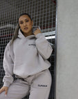 girl posing, left hand on hood, right hand on knee against cage