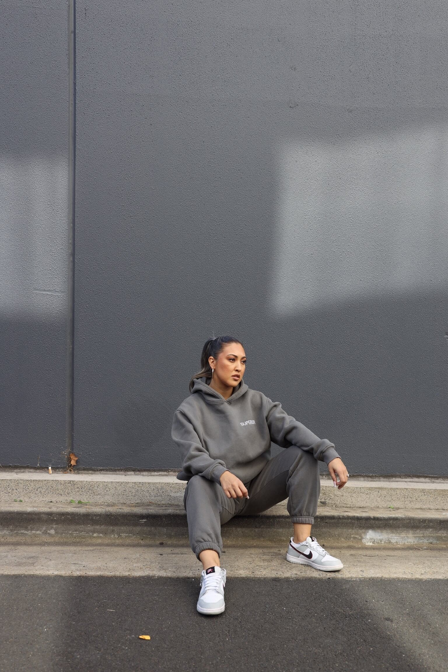 posing in streetwear clothing sitting down on gutter