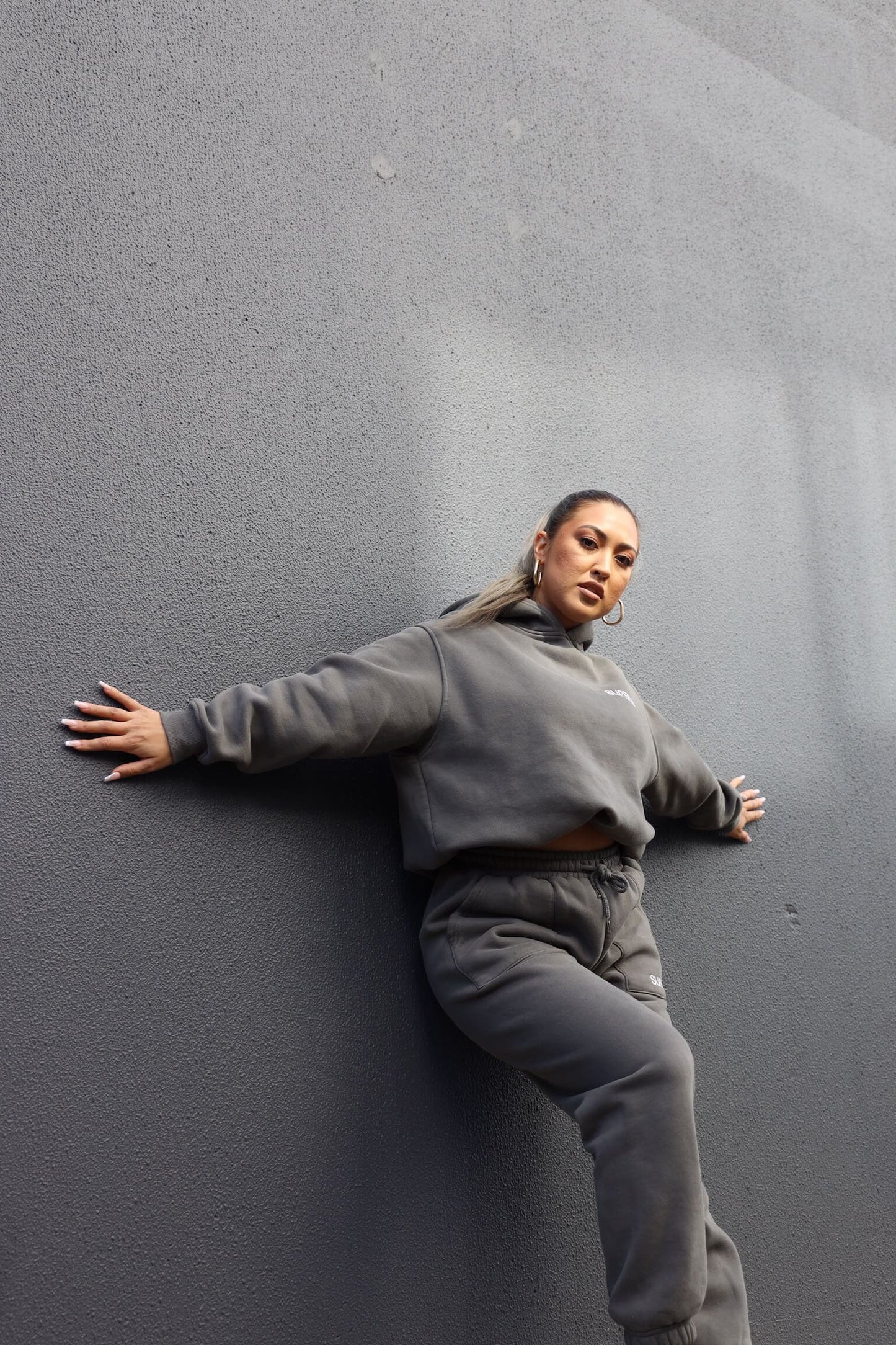 posing in streetwear clothing up against charcoal rendered wall